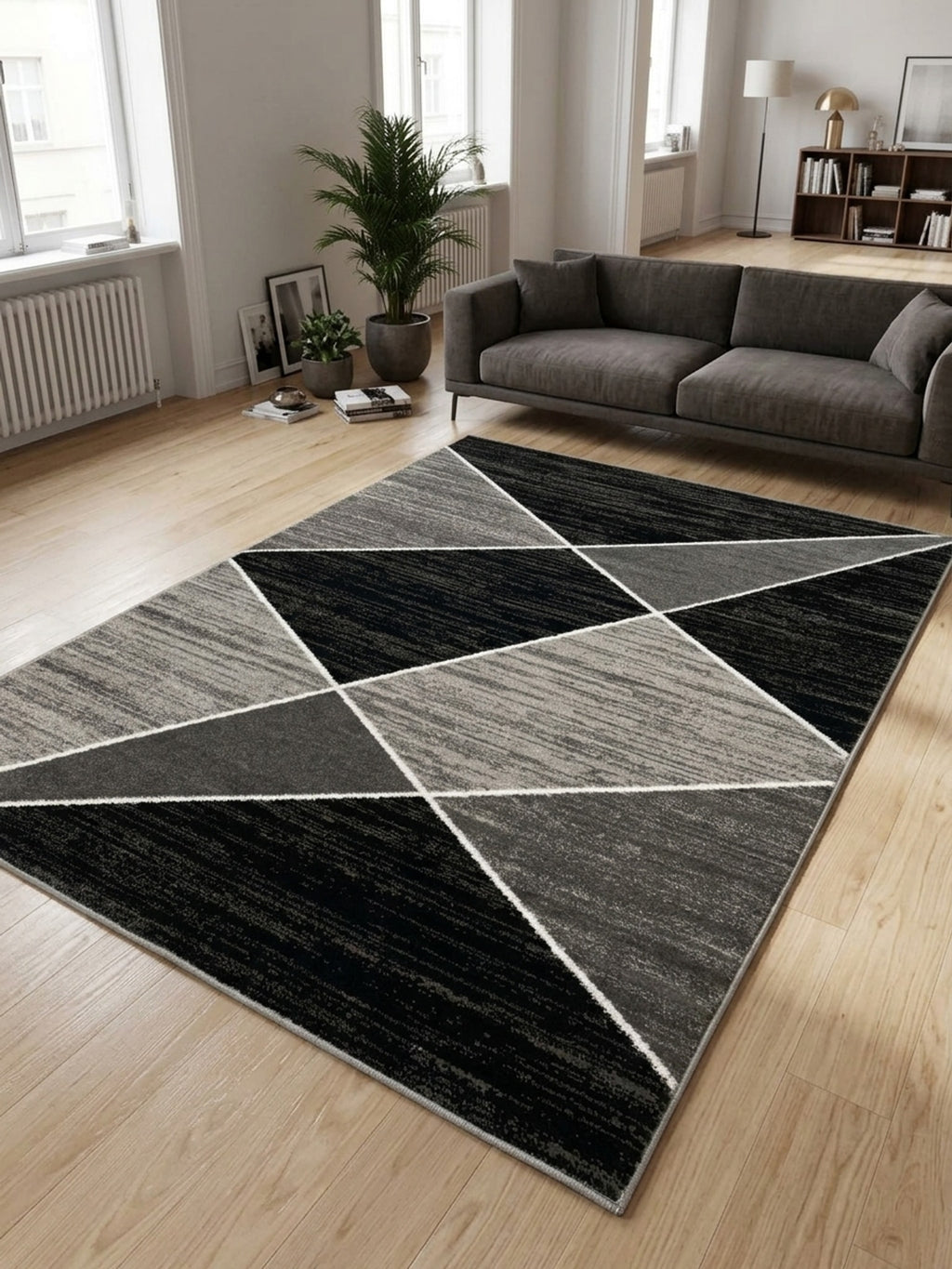 Modern, téglalap alakú szőnyeg fekete és szürke geometriai háromszögmintával, világos nappali enteriőrben.